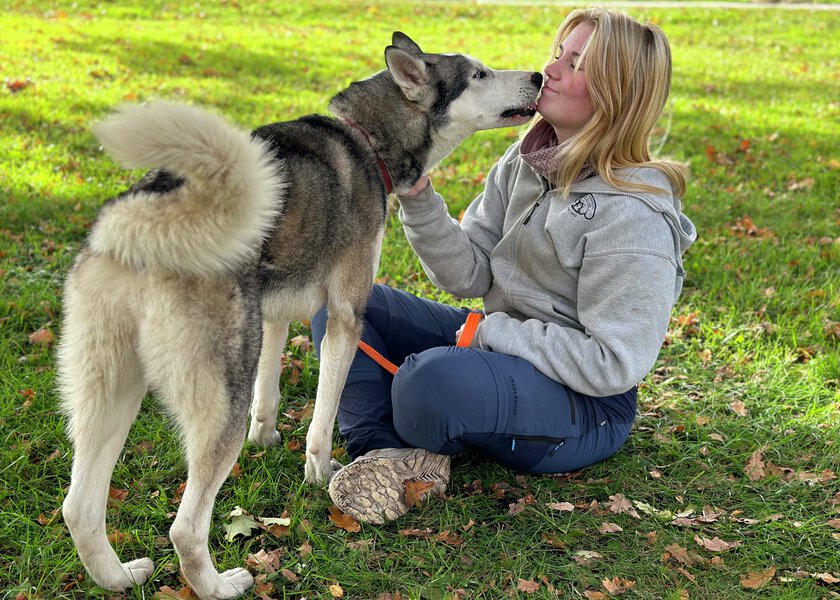 Hund som viser hengivenhet til e elev som sitter på gresset - Klikk for stort bilde